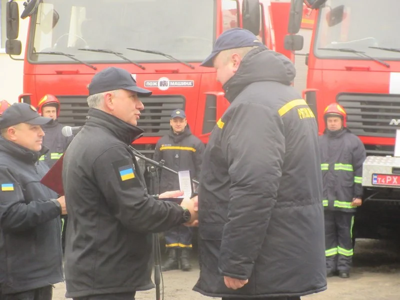 Вручення сертифіката рятувальнику ДСНС біля червоних пожежних машин