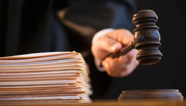 Суддя в мантії тримає дерев’яний молоток біля стопки документів
