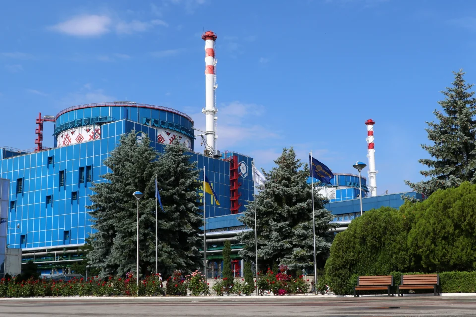 Сині корпуси Хмельницької АЕС з орнаментом, димарі, прапори та квітники